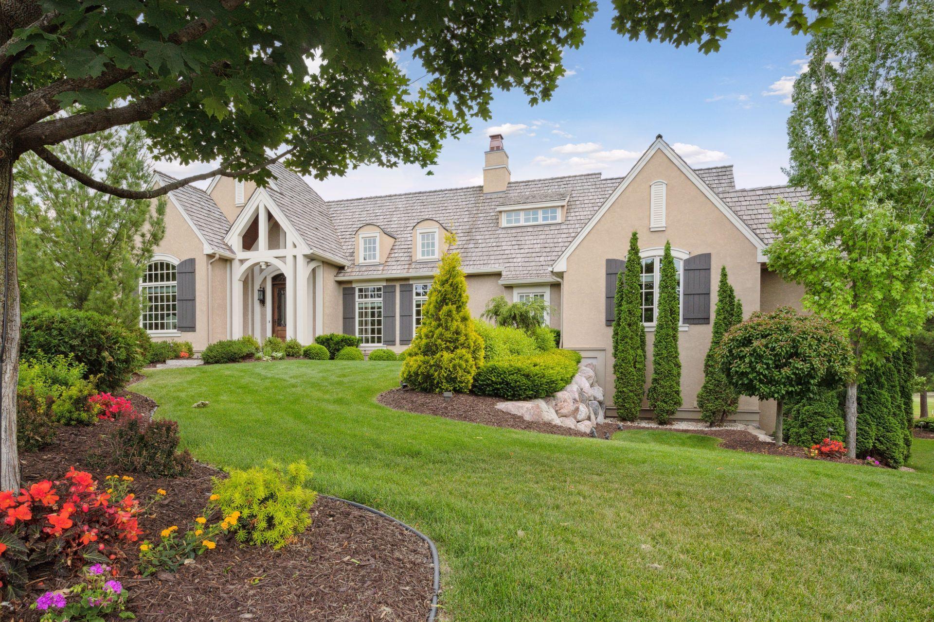 Perennial gardens, rock walls, paver approach, and mature trees all lend to the soft elegance of this home