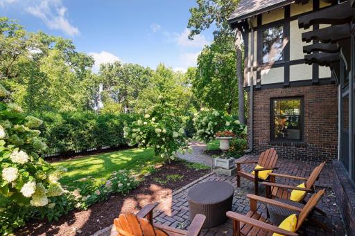 Beautiful and private front courtyard with groomed gardens surrounding a brick paver patio.