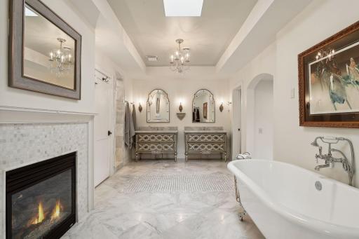 Inviting spa-like bath with two-sided fireplace, soaking tub, marble tile, double vanities, water closet, and huge walk-in shower.