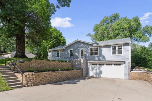 A lovely statement entrance with over-sized concrete driveway, gorgeous retaining walls, stone facade wall, and upgraded garage door.