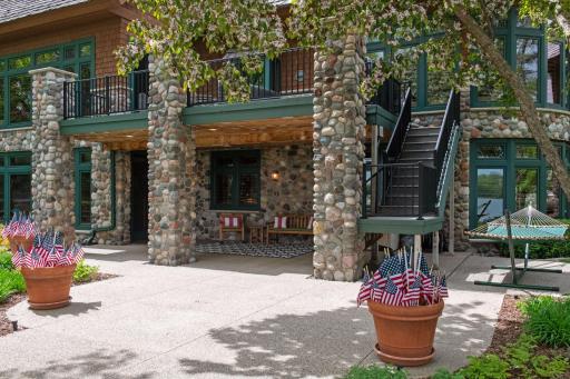 Stunning lower level covered patio complete with sound, recessed lighting / beach sconces along with staircase to deck and lower level garage door to the right not pictured.