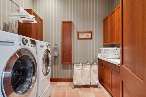 Main level laundry room with utility sink, nice folding counter tops with lots of cabinetry for storage and wall drop down ironing board.