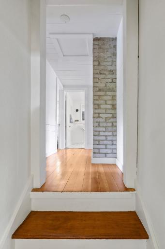2nd level hallway with original fir floors and exposed brick chimney