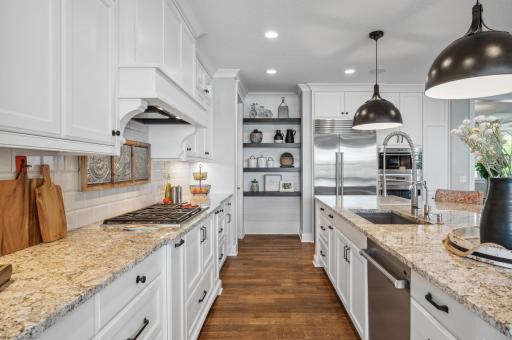 The stunning kitchen has high end finishes including granite countertops, a Wolf cooktop, oven, and microwave, and a Sub Zero refrigerator.