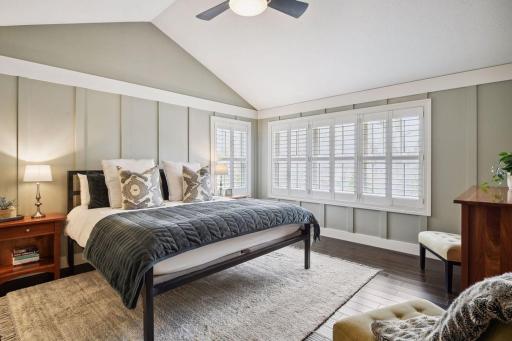 Primary Suite with hardwood floors, vaulted, wainscoting, and shuttered windows