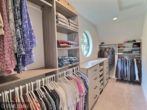 A walk-in closet you have always envisioned in an owner's suite finished with custom organization and carpet.