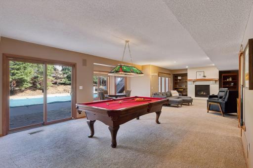 The roomy basement family room area is built for entertainment, boasting a pool table area, card playing/hobby section, TV area, and direct access to the backyard pool!