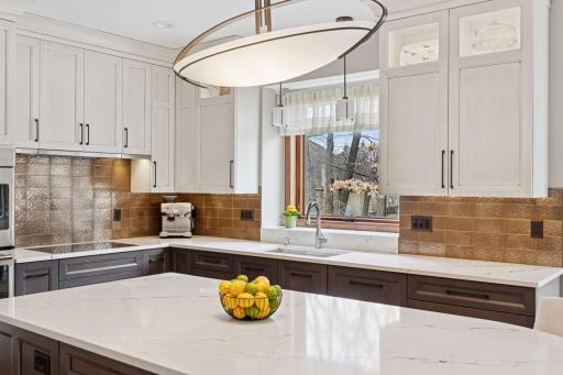 Natural light floods the kitchen, highlighting the expansive center island and gleaming copper backsplash!