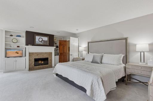 Double doors lead to a serene, expansive primary suite, anchored by a wood-burning fireplace and elegant bookcases!