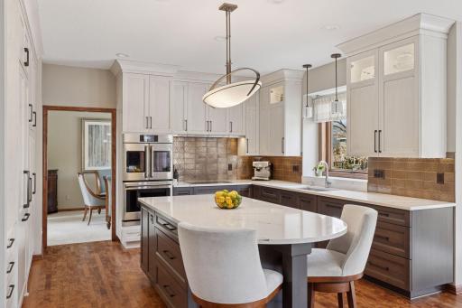 A meticulously detailed kitchen boasts full cabinets topped with crown molding. Select cabinets feature lighted glass door tops, adding a classy touch!
