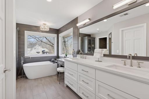 The fully remodeled primary bathroom boasts a spa-like ambiance with a double vanity, a deep soaker tub, a sleek tile shower, and luxurious flooring that elevates the entire area!