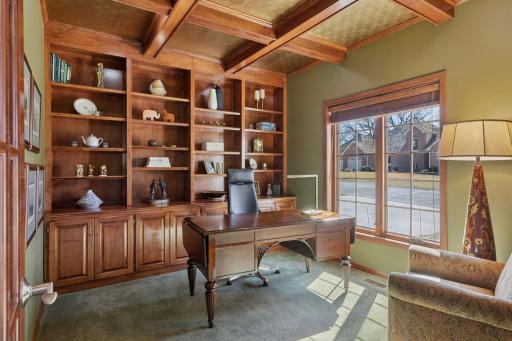 French doors open to this warm front office. Built-in shelves, rich tones, and wood blinds create a cozy, classic workspace!