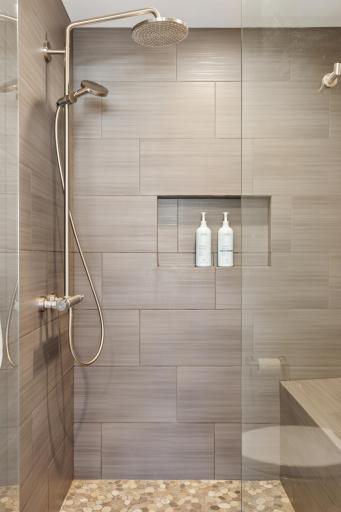 Beautiful tiled shower with glass front and convenient bench seat!