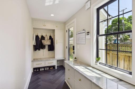 Gorgeous and sunny mudroom - quartzite benches and unlacquered brass hardware