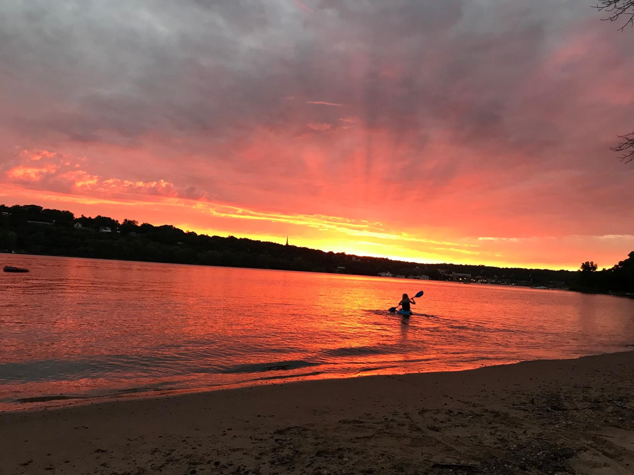 A lone kayaker leaves the beach for a sunset cruise