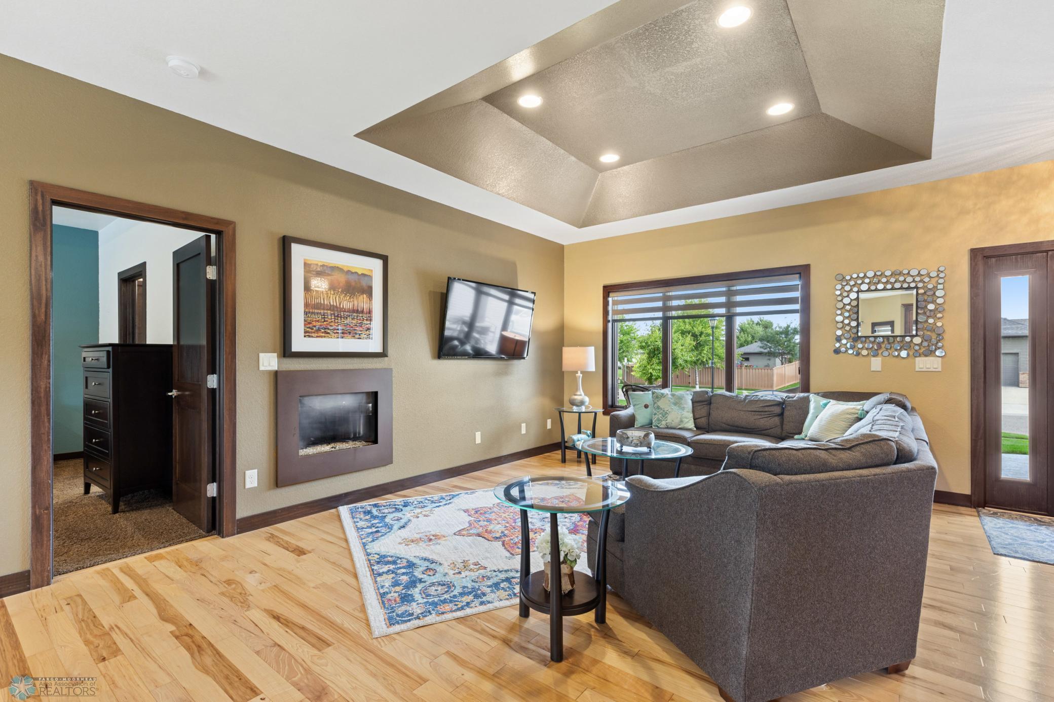 living room with gas fireplace and tray ceilings
