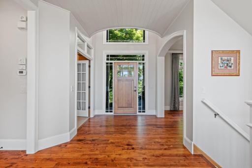 Foyer has charming solid wood entry door, rustic maple hardwood flooring and enameled wood paneled ceiling