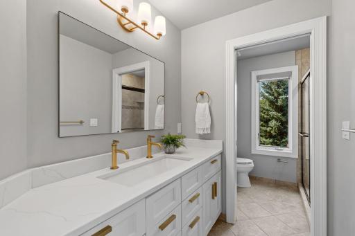 3/4 Bathroom features enameled vanity cabinet offers a quartz top, modern sink and two faucets. Separate room for shower and toilet w/ pocket door access and linen closet with tile flooring
