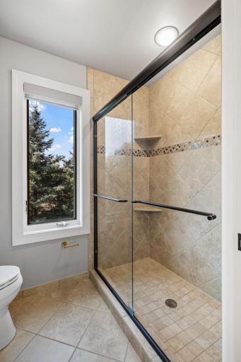 Large shower features full tile surround and semi-frameless glass doors