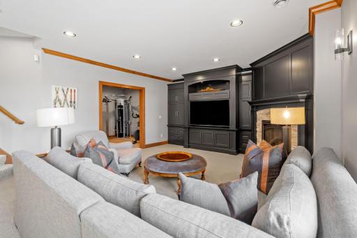 Lower level Family Room features built-in entertainment cabinet that offers storage with interior lighting, open display with lighting and area for a modern TV
