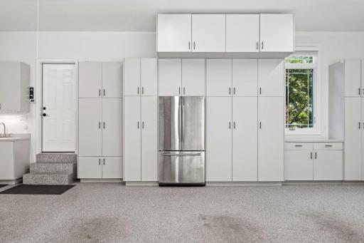 Abundance of storage cabinetry w/ utility sink and countertop. Additional entry door with access to the paver sidewalk and patio area. Installed air compressor hose and attachments.