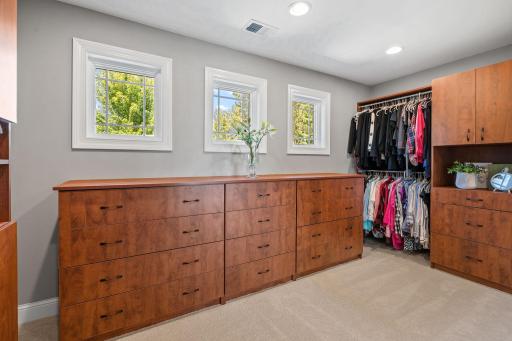 Generously sized walk-in closet offers custom storage organizer, laundry chute and natural light