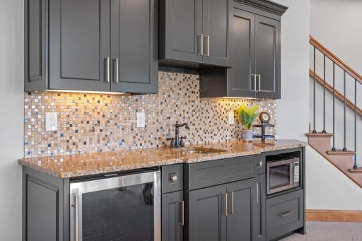 Wet Bar features enameled cabinetry, granite countertops with mosaic tile
backsplash, beverage refrigerator and microwave