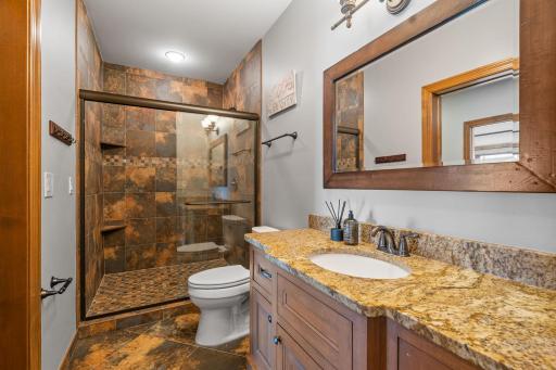3/4 bathroom features custom walk-in shower that offers full tile surround and semi-frameless glass shower doors. Wood vanity cabinet with granite top