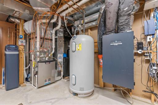 Spacious storage area with built-in shelving in the Mechanical Room. Water softener systems replaced in 2021