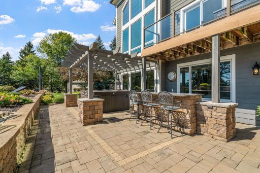 Additional paver patio area offers a pergola, bar with granite top and area for a hot tub