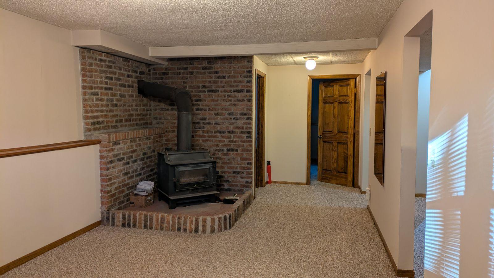 Lower-Level Amusement room with wood burning stove said to be capable of heating the whole house!!! Doors to BR3 and bath also seen in this view.