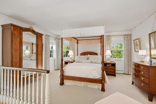 French doors open onto the primary suite, and a door with transom windows leads to an outdoor, second-floor porch shaded by trees.