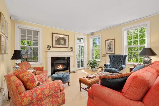 A stunning family room with a gas fireplace with a carved mantle decorated in the Federal style, and wool carpet.