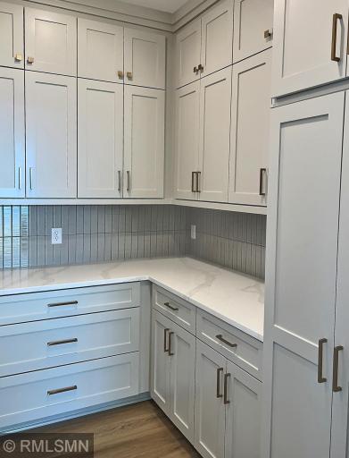Area off the kitchen with even more cabinets and counter space, the 'butlers pantry' includes quartz countertop and tile backsplash.