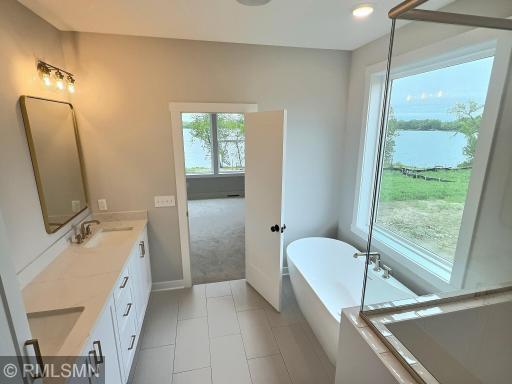 Relax in this gorgeous soaking tub in the primary bathroom, an open glass shower is complete with wonderful custom tile work.