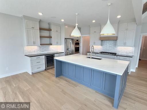 Stainless steel appliances, custom tile backsplash and exhaust hood, open shelves and pendant lights make up this dreamy kitchen.