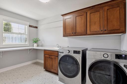 The well-appointed laundry room offers tiled floors, a sink, and ample storage and countertops for folding.