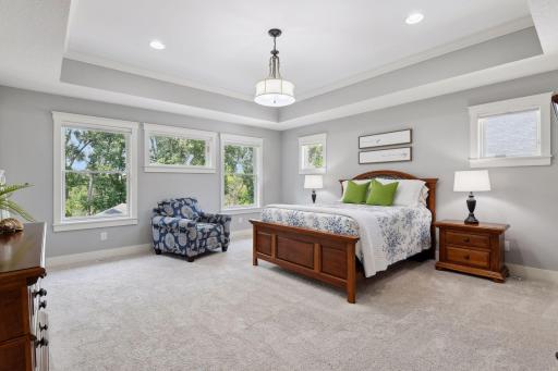 The star of the upper level is the luxurious primary suite, offering breathtaking backyard views, intricate ceiling details, and a chandelier.