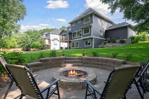 The expansive backyard, shaded by mature trees, features a fireplace.
