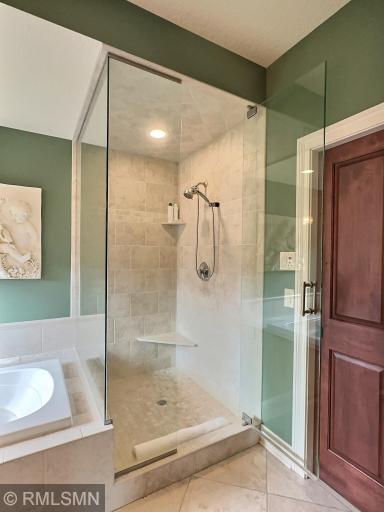 Custom tile work throughout this primary suite, including this shower and floors. Additional walk in closet here as well..