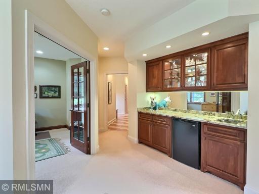 Lower level wet bar, with built in cabinetry, granite countertop, and bar sink.