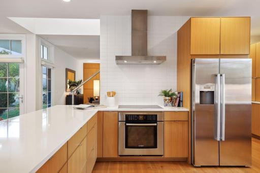 Induction cooktop with wall oven and ventilating hood.
