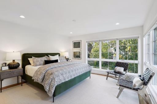 Serene and spacious primary suite with a corner of windows overlooking tree tops. The natural light in this home is extraordinary.