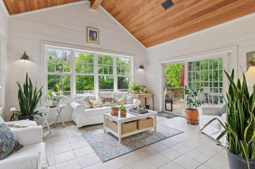 Light and bright four seasons porch with in floor heat, views of the lush outdoor space, and access to the large back deck