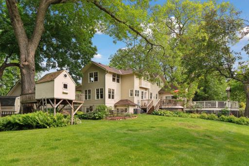 Expansive backyard with a large lawn and charming playhouse ideal for easy indoor/outdoor living and entertaining