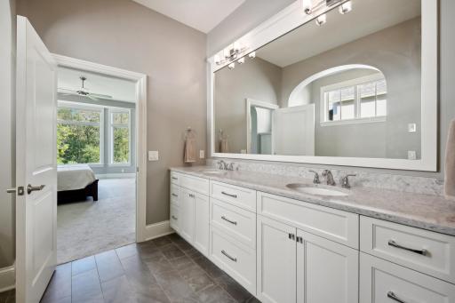The primary bath is well equipped with heated tile flooring, granite comfort counters and Shelf Genie pullout drawers