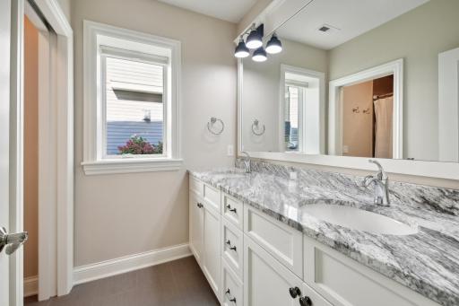 The full bath serves both guest bedrooms and features a double vanity, granite countertops, pullout shelving and a tiled surround tub