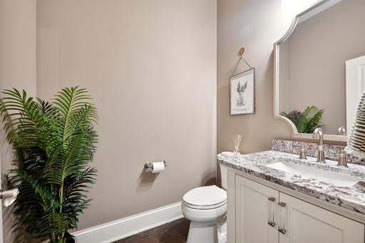 The powder room has a designer mirror and granite countertop