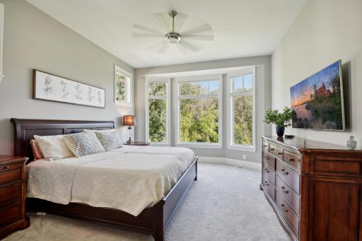 The main floor primary bedroom overlooks the wooded backyard