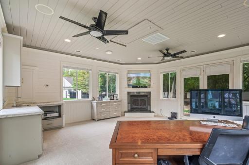 An additional stand-alone outbuilding with carpeting, a gas-burning fireplace, and a built-in wet bar is a versatile space that can serve as a business room or a place for various recreational activities.